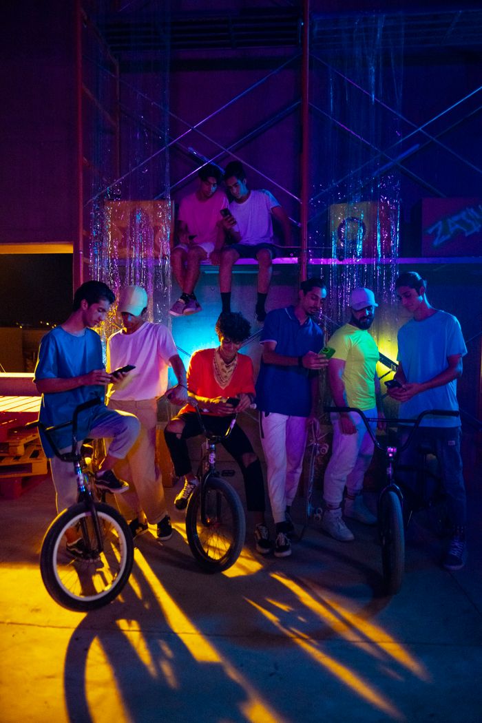 Group of teenagers enjoying a night indoors with bicycles, using smartphones.